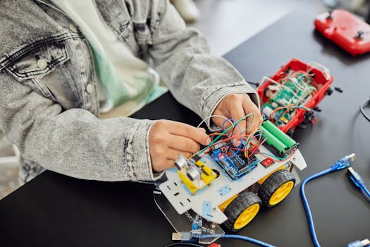 Young student assembling a toy car with electronic components, focusing on STEM education.