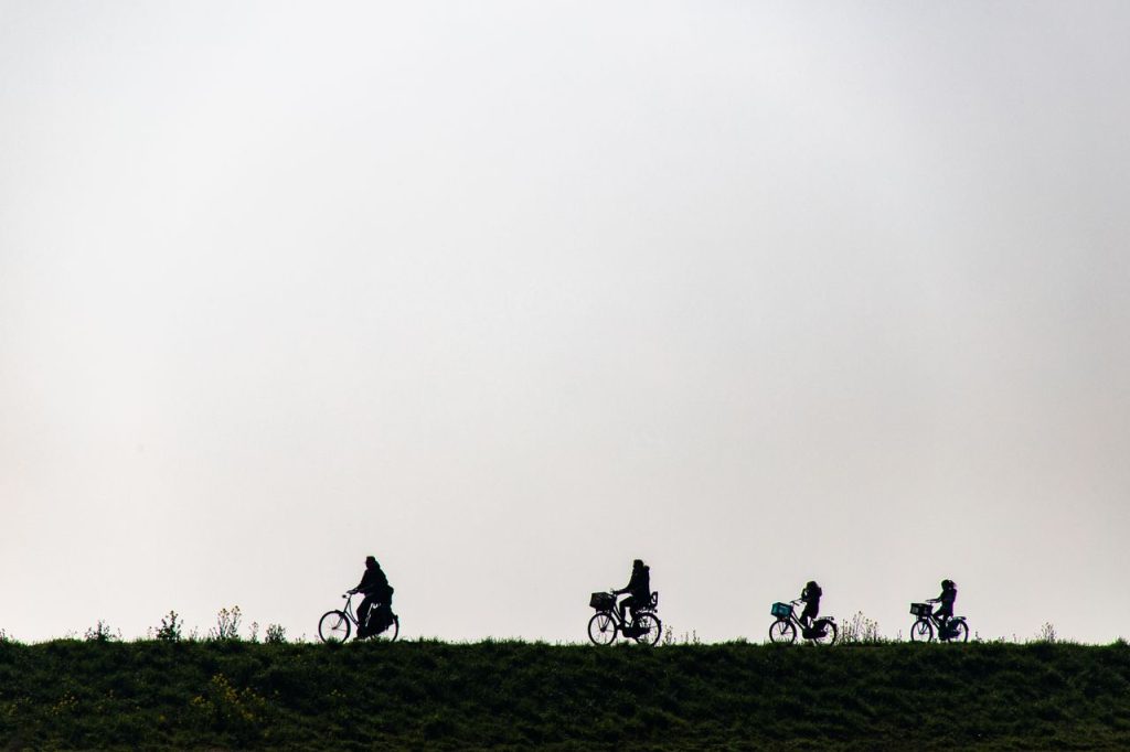 Family cycling in silhouette on a scenic dike in Marken, Netherlands, perfect for leisure and bonding moments.