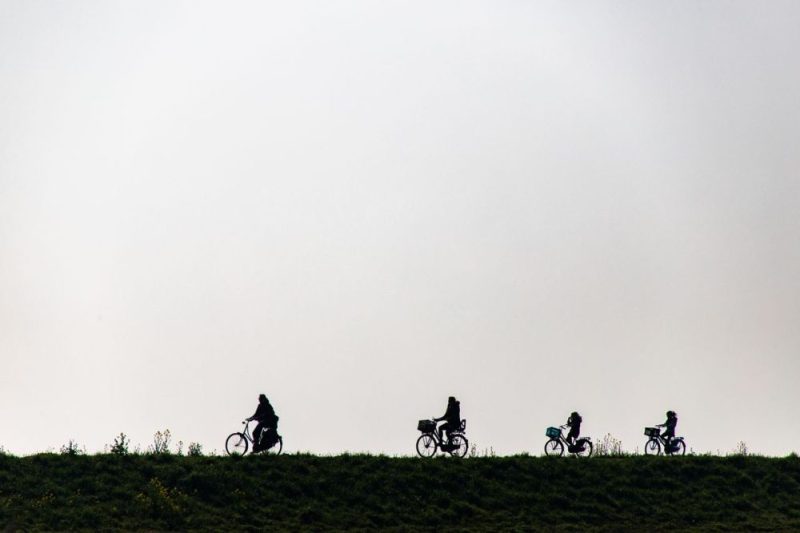 Family cycling in silhouette on a scenic dike in Marken, Netherlands, perfect for leisure and bonding moments.